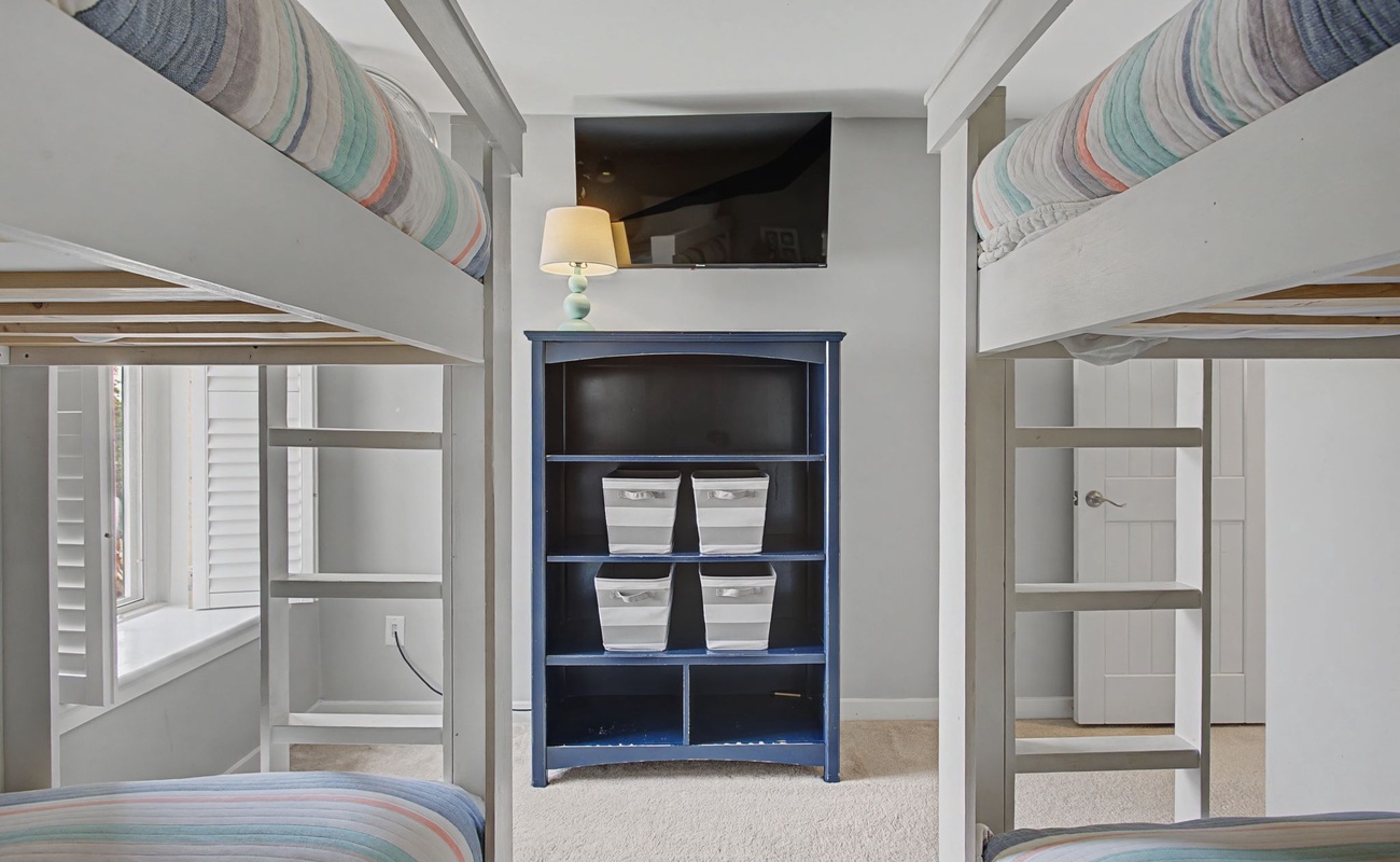 Your family will love this cheerful bunk room with four comfortable beds, organized storage, and a mounted TV for movie nights together.