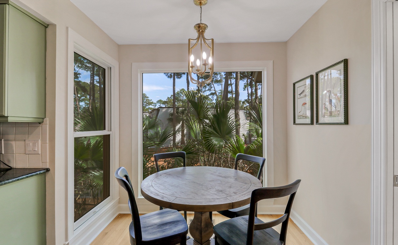 Gather around this cozy dining nook where meals become memorable moments, framed by lush tropical views through expansive windows.