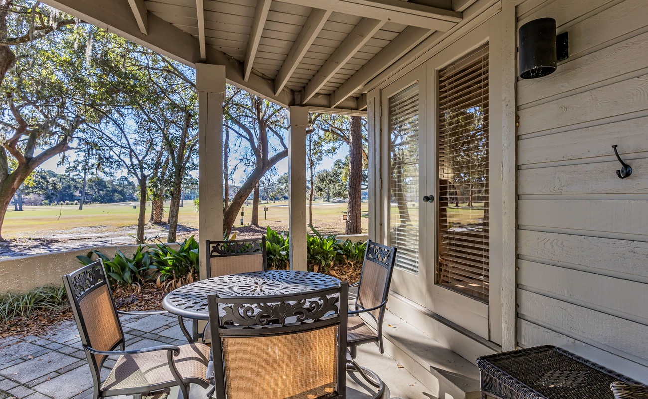 Enjoy morning coffee on your private covered patio, where comfortable seating and peaceful park views create the perfect outdoor retreat.