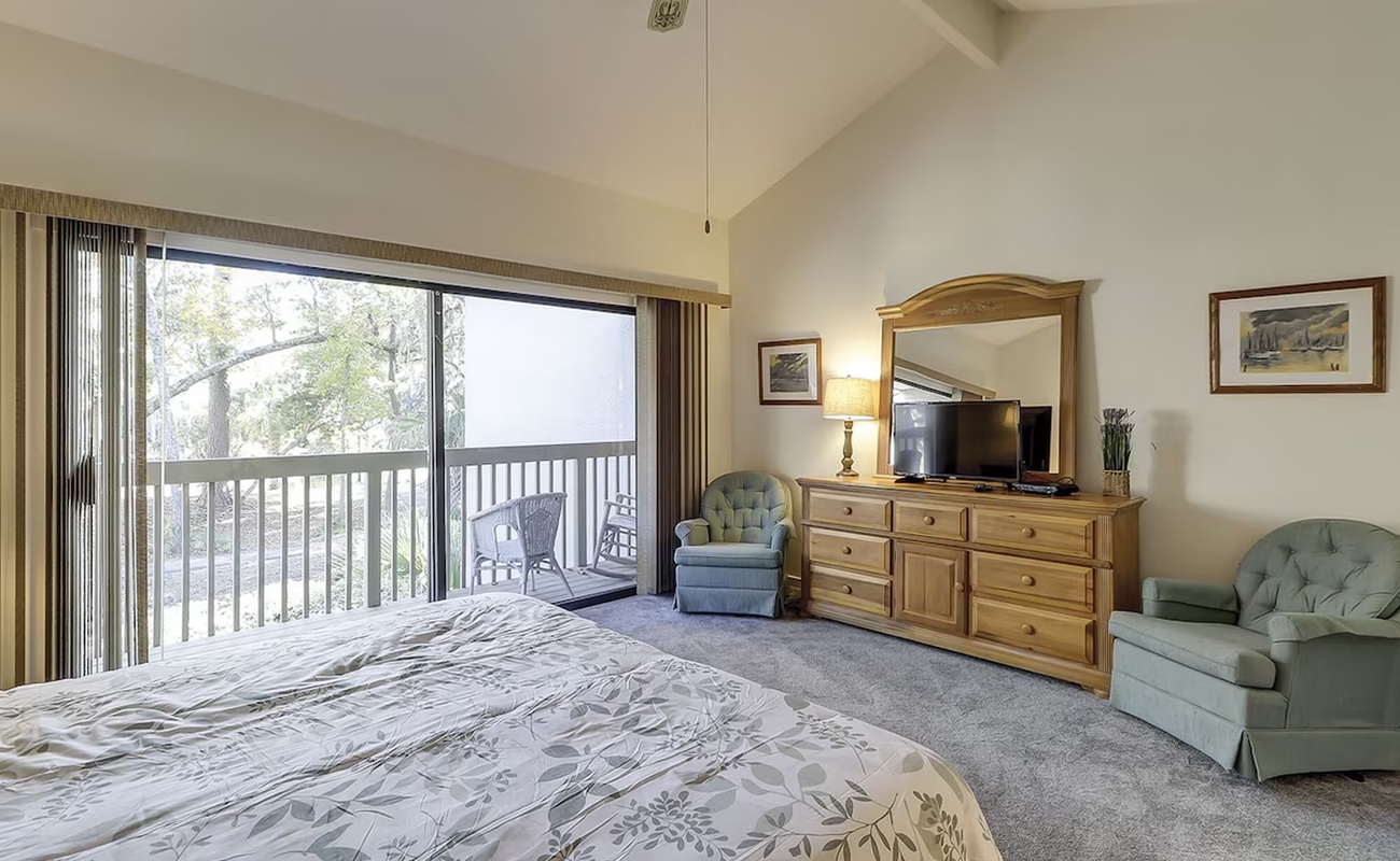 Relax in your spacious bedroom with charming balcony views. Enjoy natural light streaming through large windows and unwind in comfortable seating.