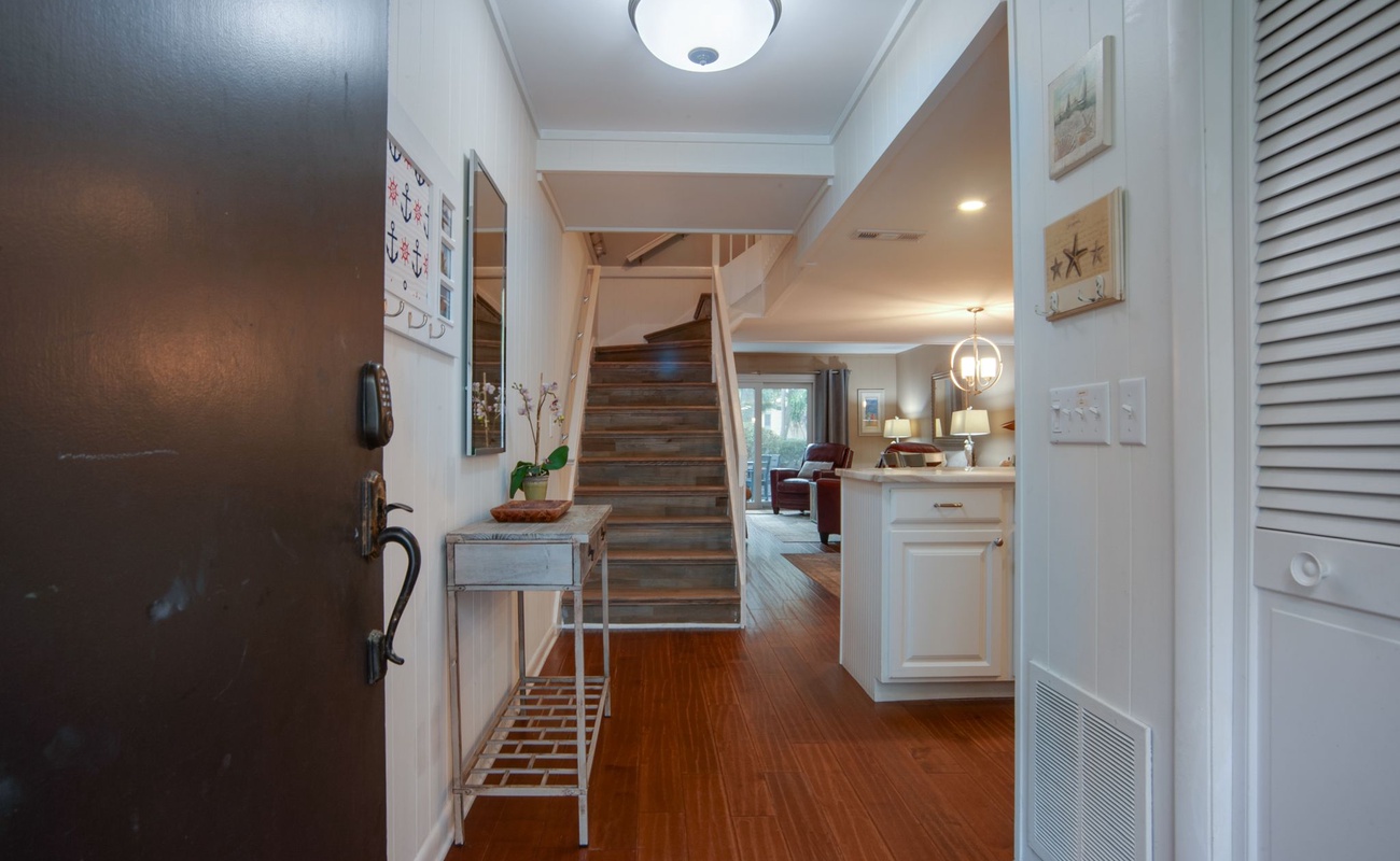 Step into your welcoming entryway where warm hardwood floors and coastal charm create the perfect homecoming feeling.
