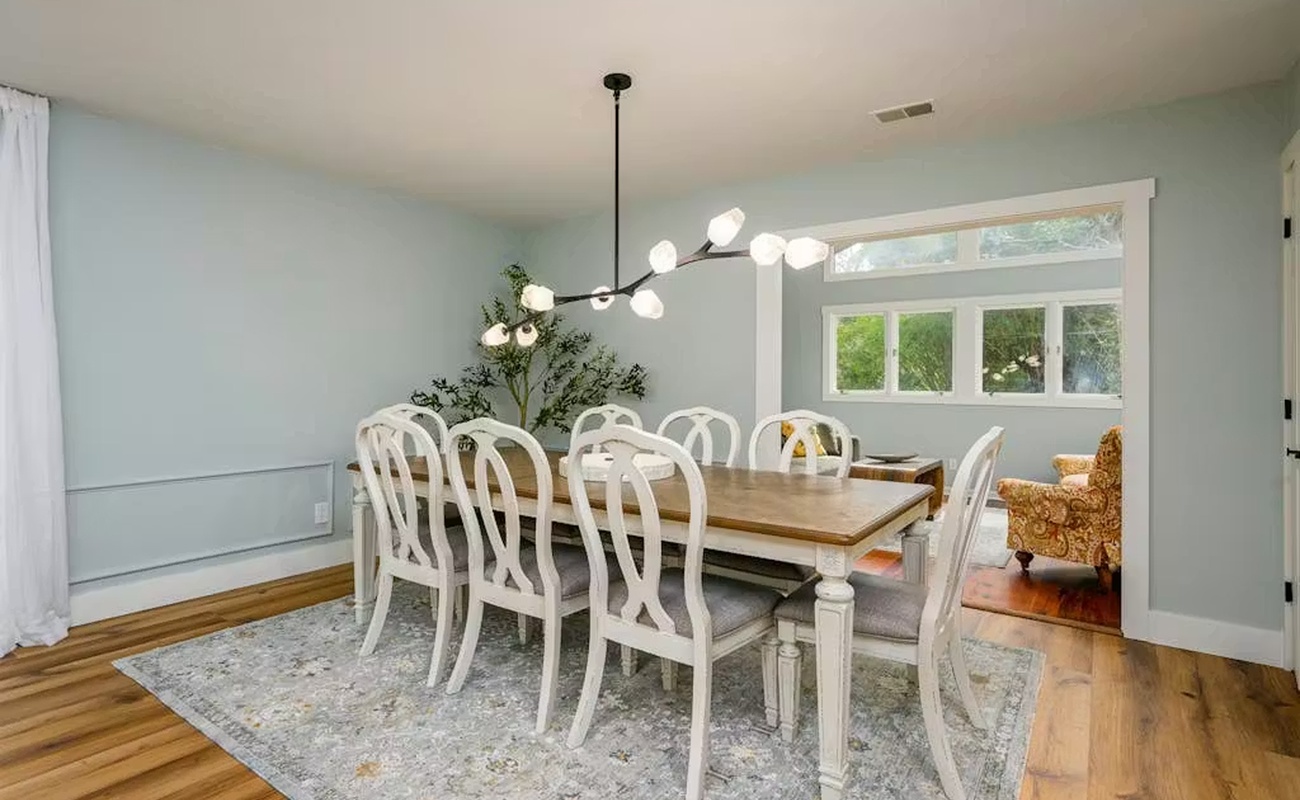 You'll love gathering around this elegant dining table, where natural light streams through large windows and modern pendant lighting creates the perfect ambiance for memorable meals.
