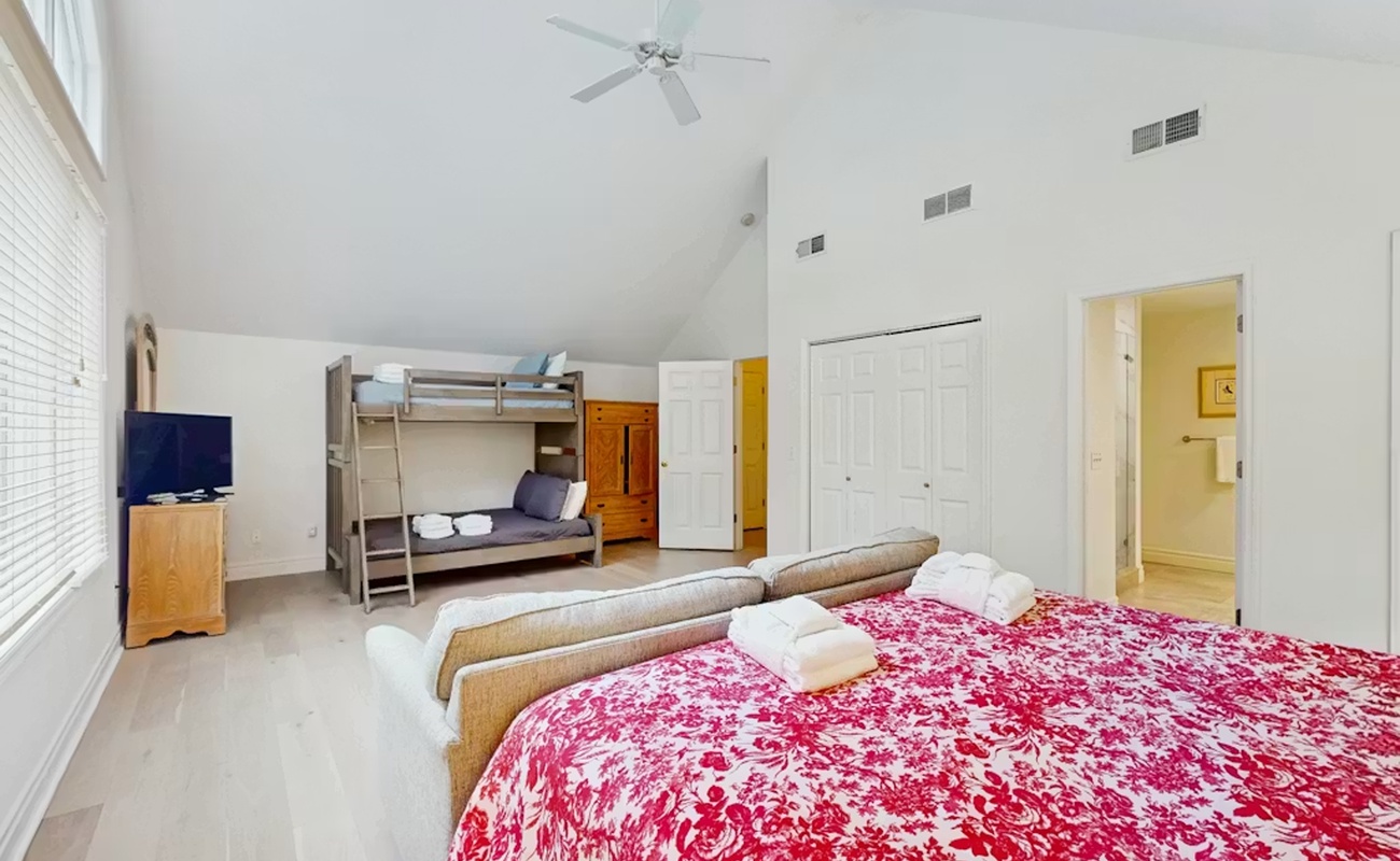 Rest comfortably in your spacious bedroom featuring a queen bed with soft linens, bunk beds for extra guests, and refreshing ceiling fan.