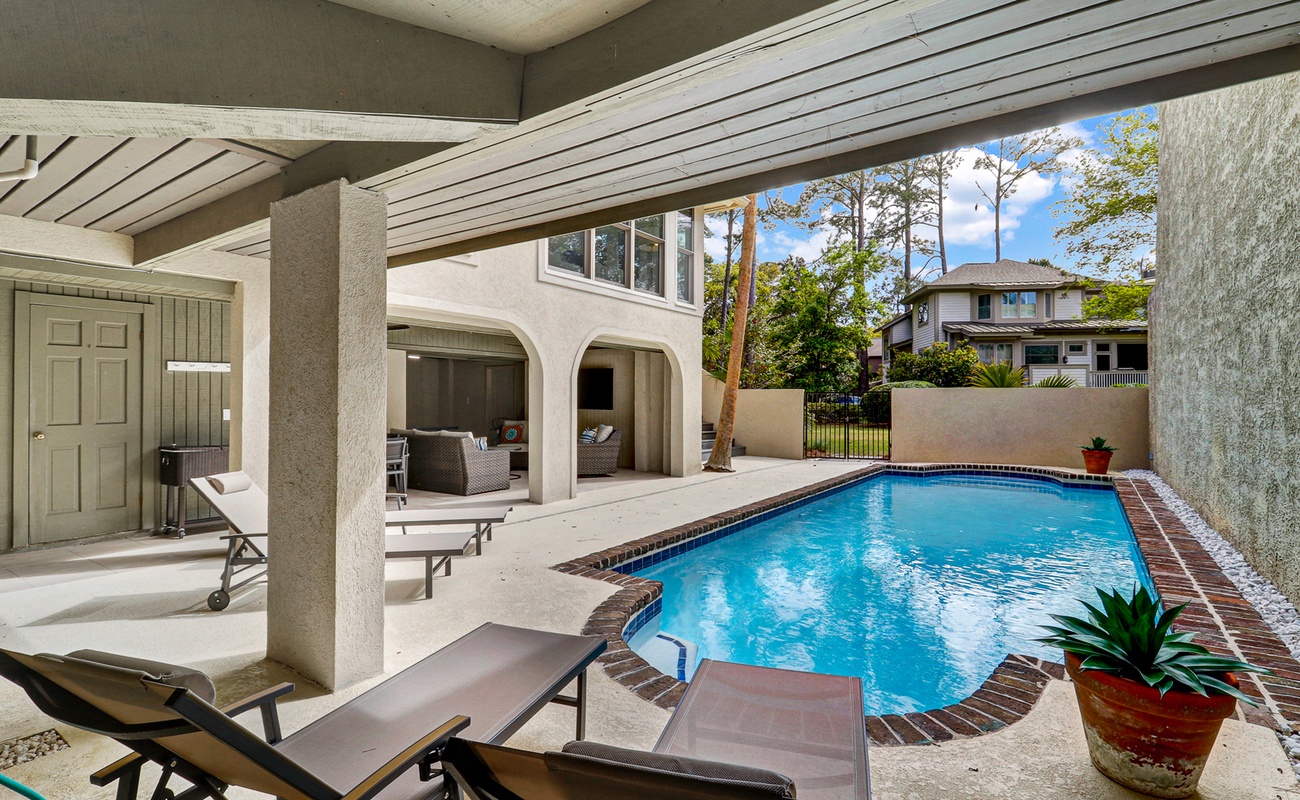 Expansive pool area with covered patio seating, multiple lounging spaces, and a private deck, offering comfort and flexibility for outdoor living and entertaining.