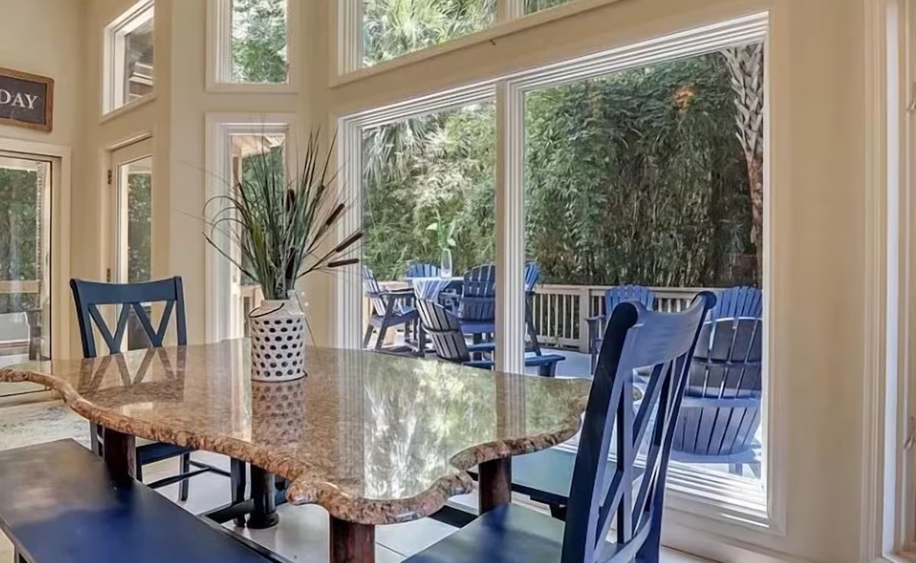 Gather around this elegant granite table where morning coffee tastes better with garden views streaming through floor-to-ceiling windows.