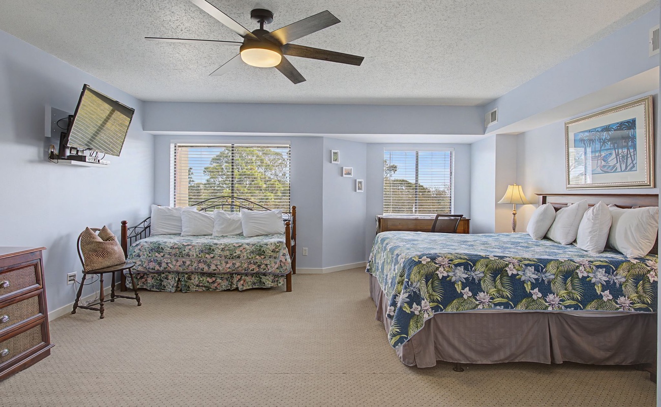 Sleep peacefully in your spacious room with tropical-themed bedding, modern ceiling fan, and views of lush greenery through your private windows.