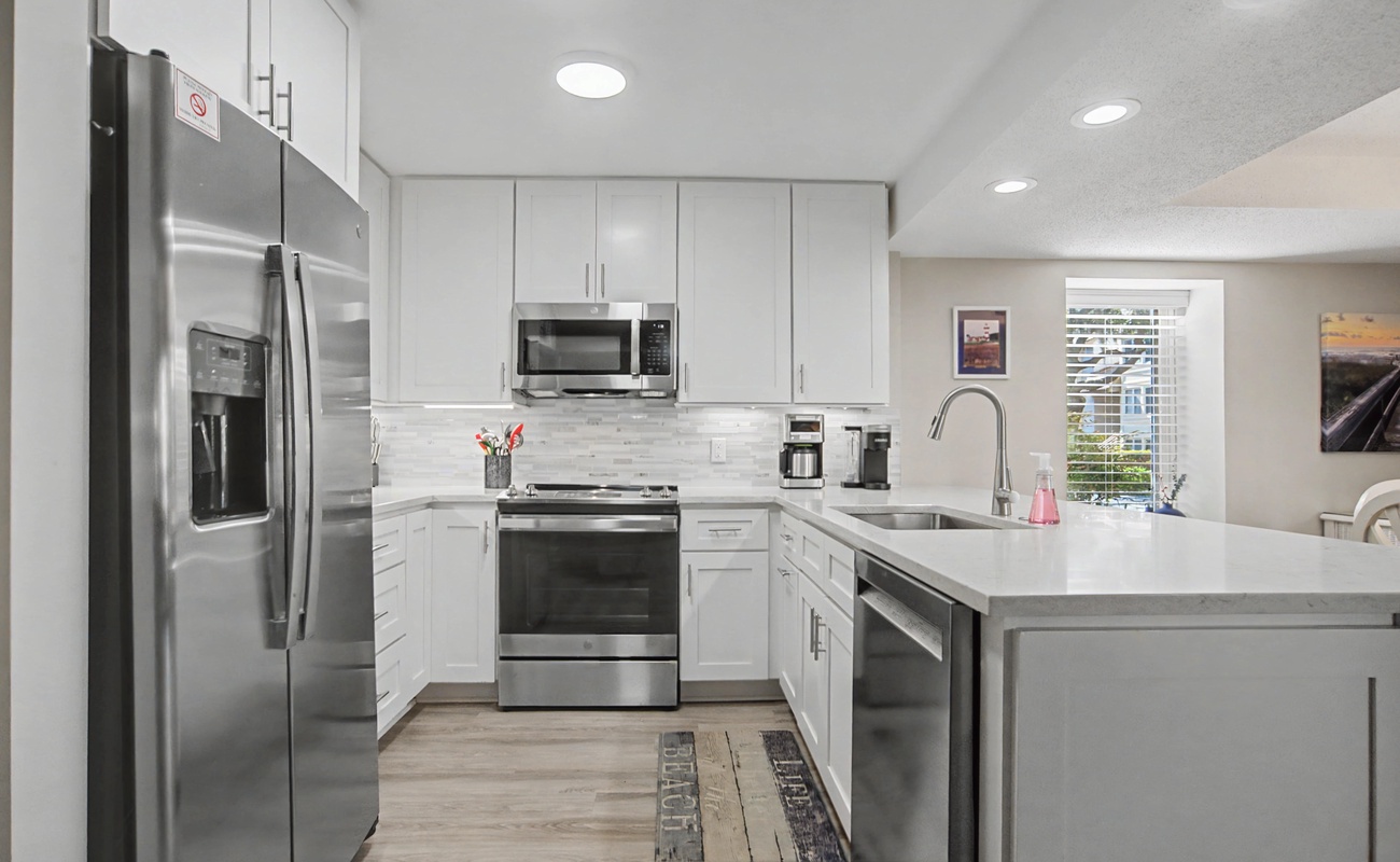 Your fully equipped modern kitchen features sleek white cabinets, stainless steel appliances, and plenty of counter space for preparing meals during your stay.