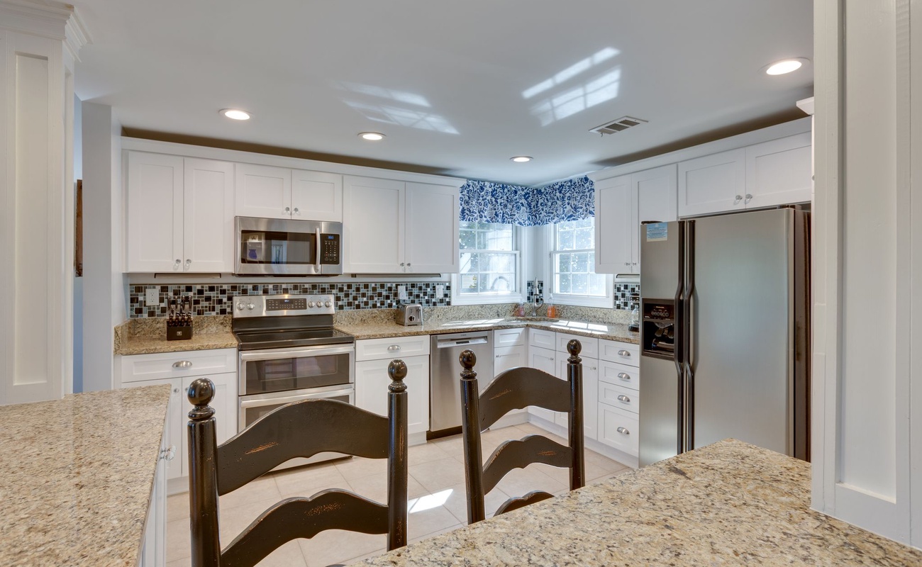 Your fully equipped kitchen features granite counters, modern appliances, and charming breakfast bar perfect for morning coffee.