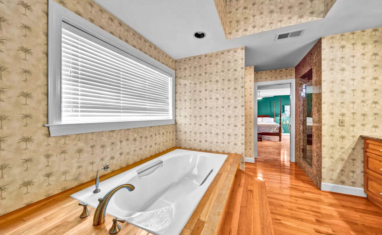 Unwind in your private spa-like retreat with a luxurious soaking tub surrounded by warm wood floors and tropical wallpaper.