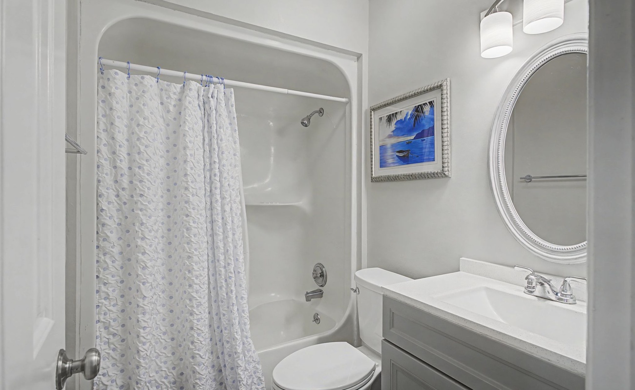 Step into your pristine bathroom featuring a relaxing tub-shower combo, elegant vanity, and thoughtful coastal artwork that adds serenity to your daily routine.