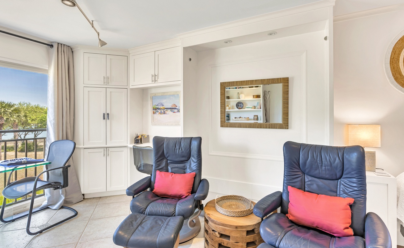 Sink into plush leather recliners with vibrant accent pillows while enjoying natural light streaming through your private balcony doors.