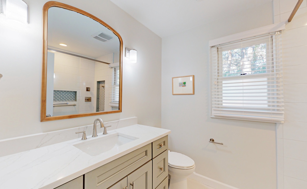 Freshen up in this elegant bathroom with its marble vanity, warm wood accents, and natural light streaming through the window.