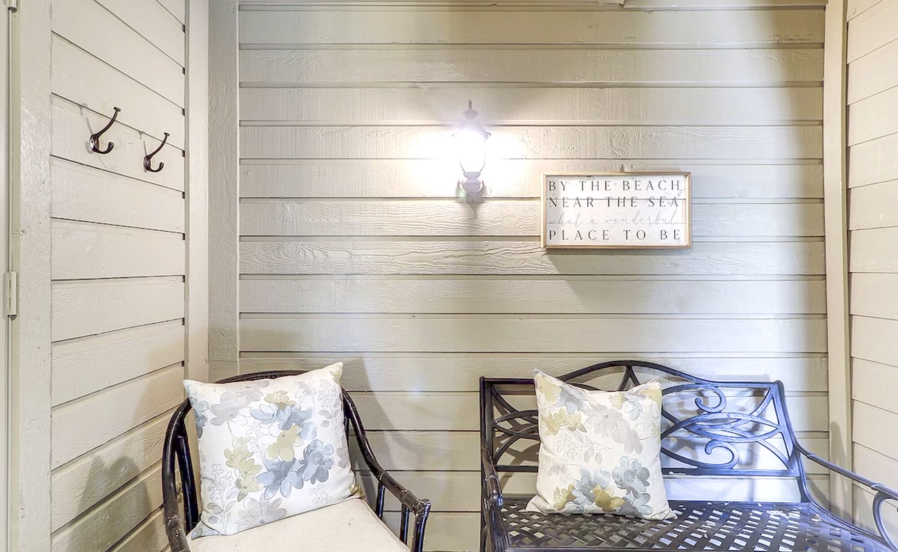 Settle into your cozy coastal corner with soft floral pillows and charming shiplap walls that whisper seaside serenity.