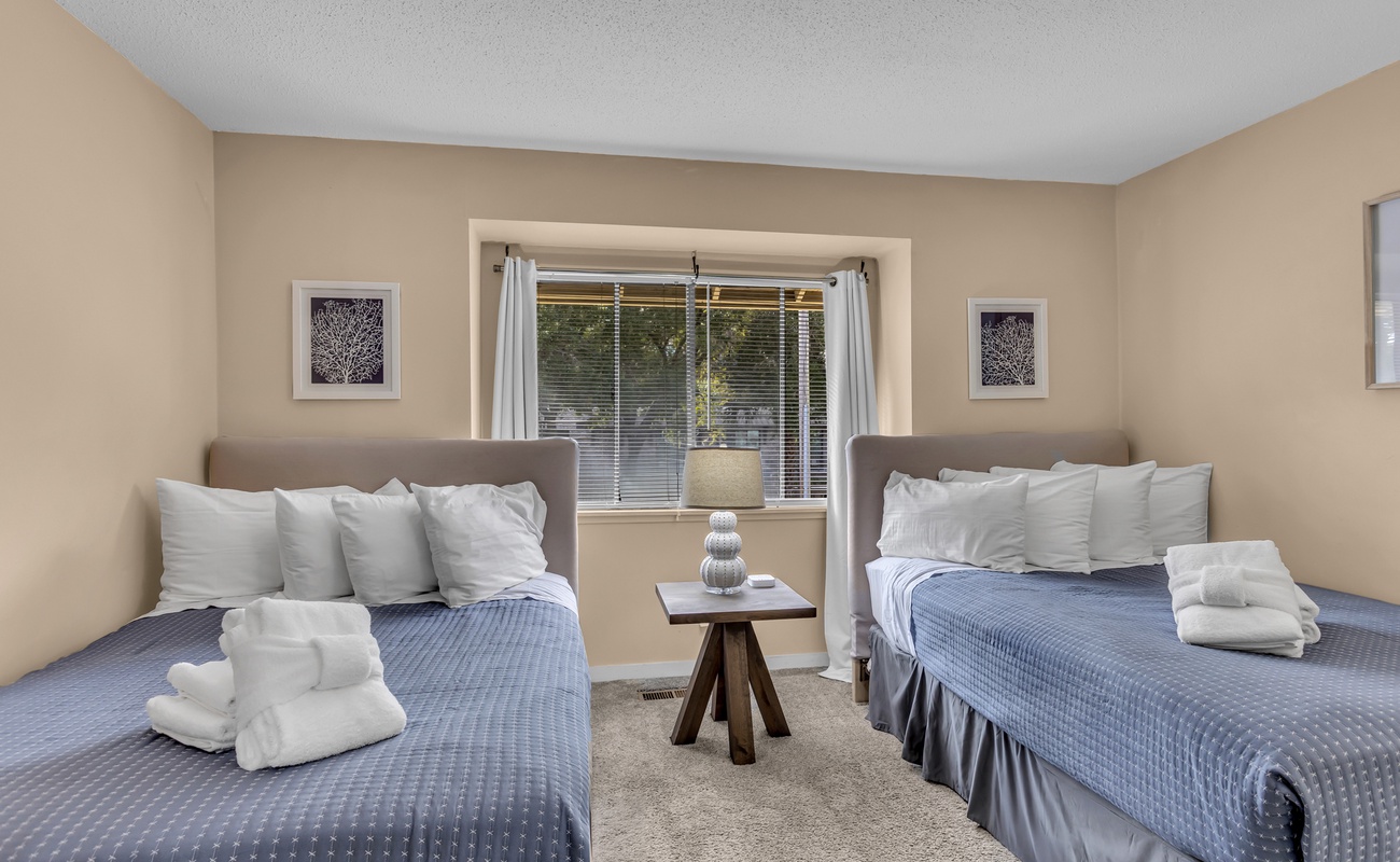 Rest peacefully in your twin bed setup, complete with plush towels and soft blue linens in this sunny, well-appointed room.