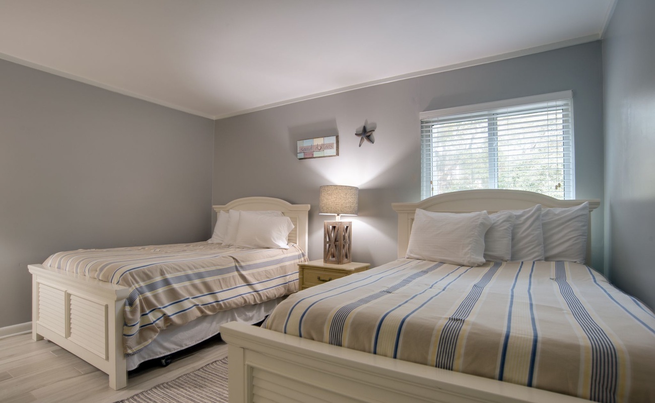 Drift off peacefully in your comfortable twin beds with soft striped linens and warm coastal charm throughout this serene bedroom.
