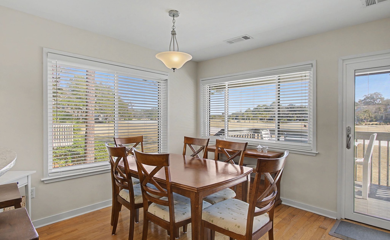 Gather around this warm dining space where natural light streams through multiple windows, creating the perfect setting for memorable meals together.