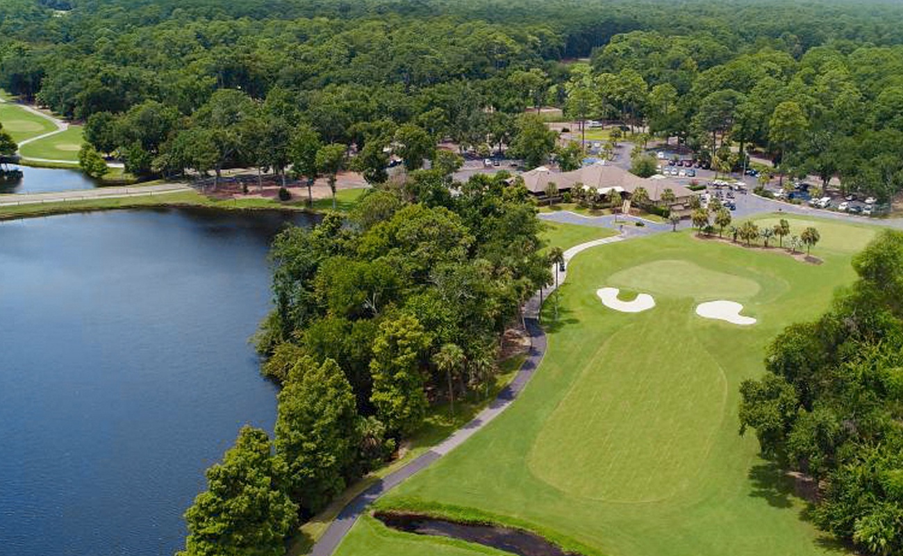 Aerial view of the golf course and lakefront resort property surrounded by lush forest canopy.