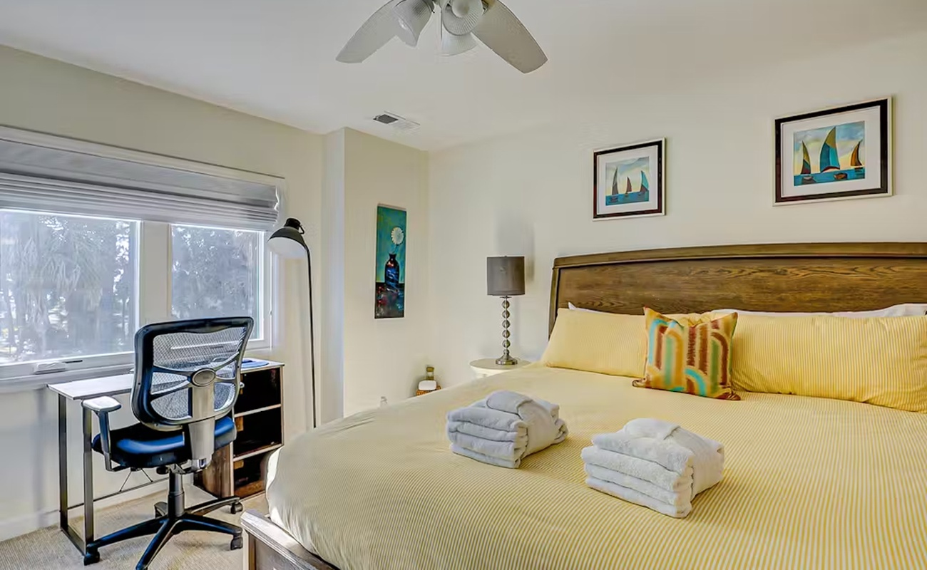 Unwind in your bright bedroom with fresh linens, workspace, and peaceful garden views through large windows.