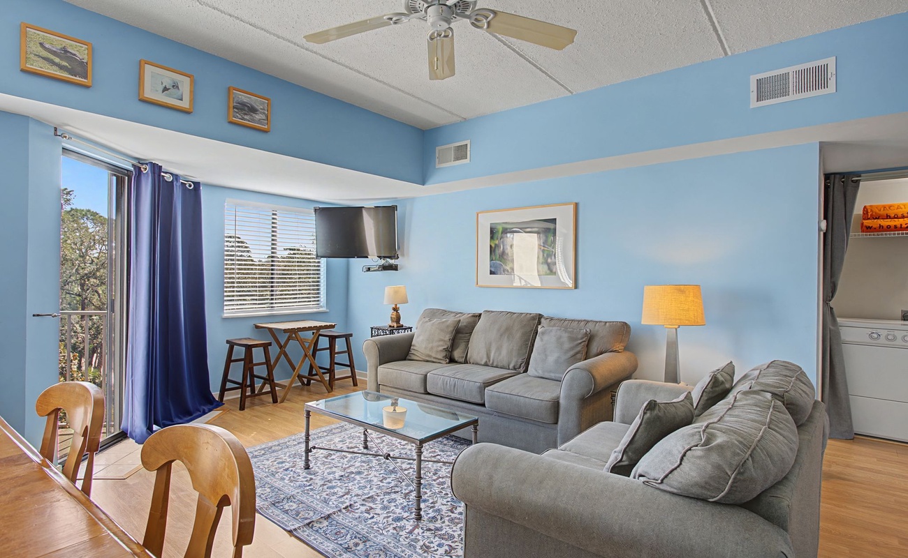 Relax in your bright living space with plush seating, warm lighting, and refreshing blue walls that create a coastal vibe.
