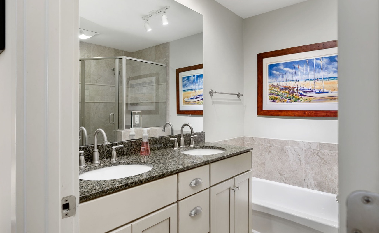 Unwind in your elegant bathroom featuring dual sinks, granite countertops, and a relaxing tub-shower combo with coastal artwork.