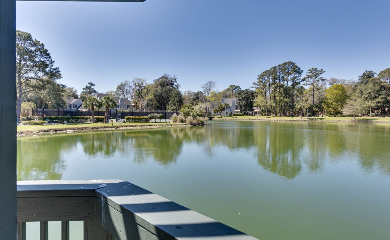 Lakefront view from covered porch showcases peaceful waters and wooded residential shoreline.