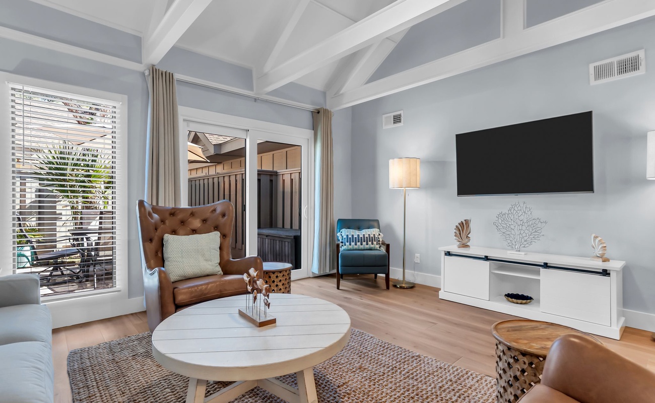 Unwind in your stylish living room with exposed beams, cozy leather seating, and patio access for perfect indoor-outdoor flow.