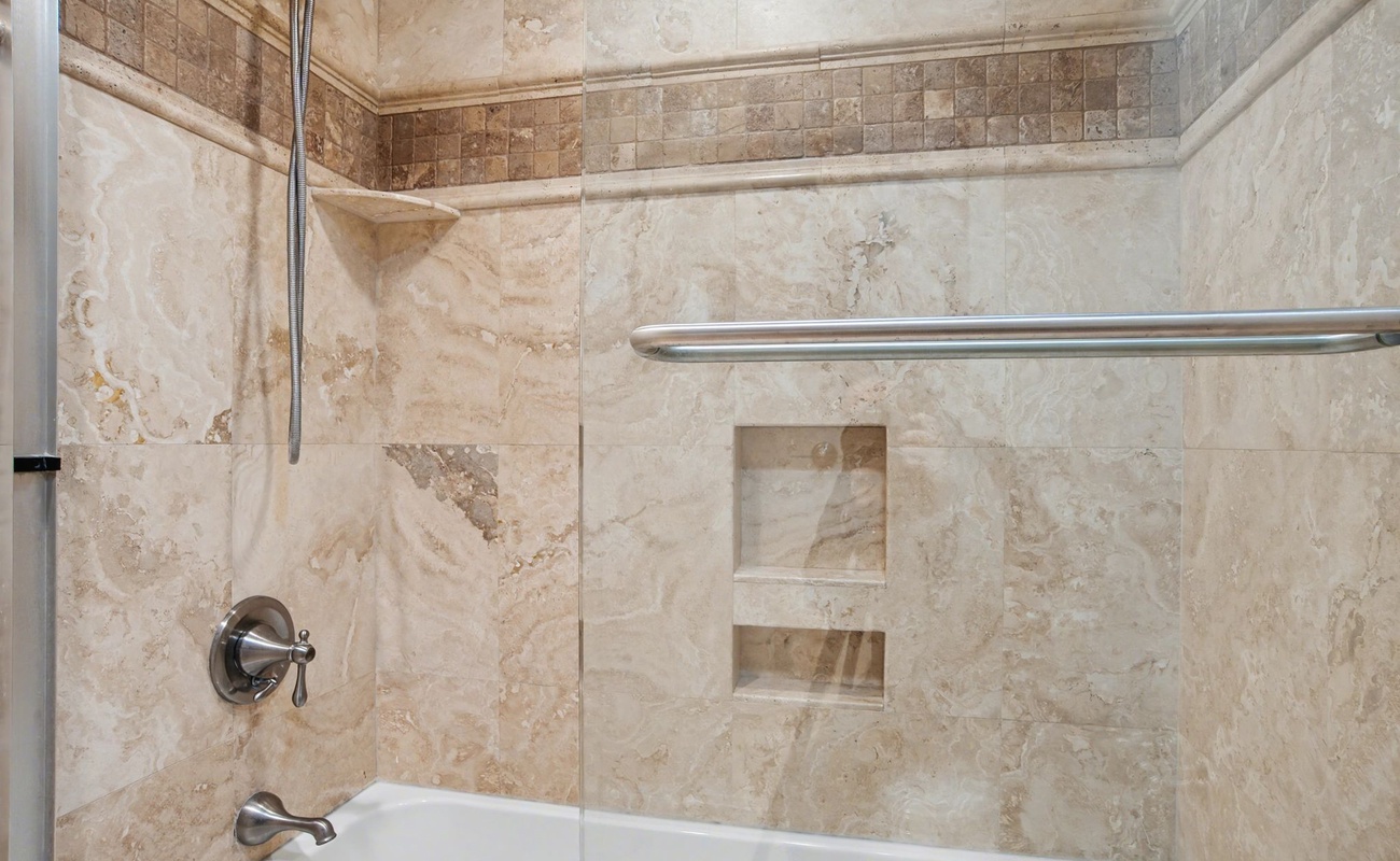 Indulge in your private marble-lined bathroom featuring elegant travertine tiles, built-in storage niches, and a luxurious soaking tub.
