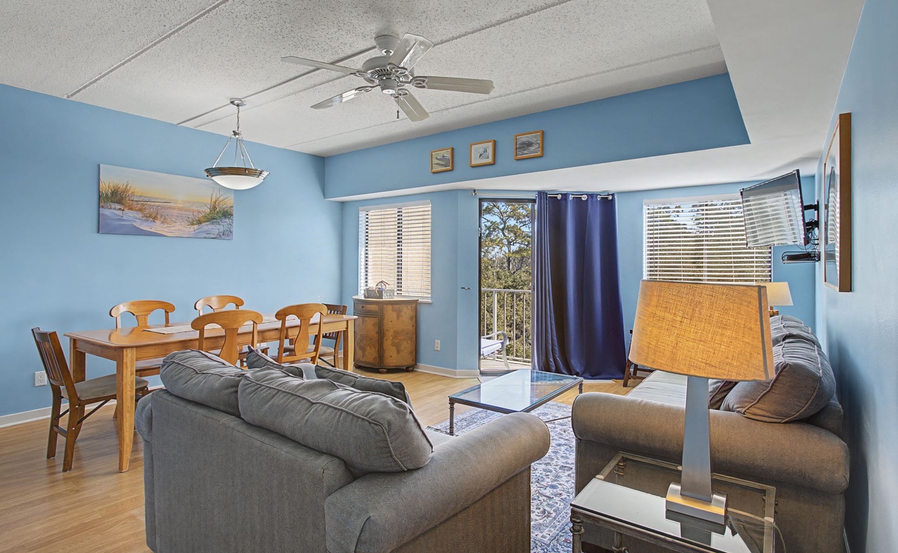 Relax in your bright, coastal-themed living space where soft blue walls and comfortable seating create the perfect atmosphere for unwinding after your adventures.