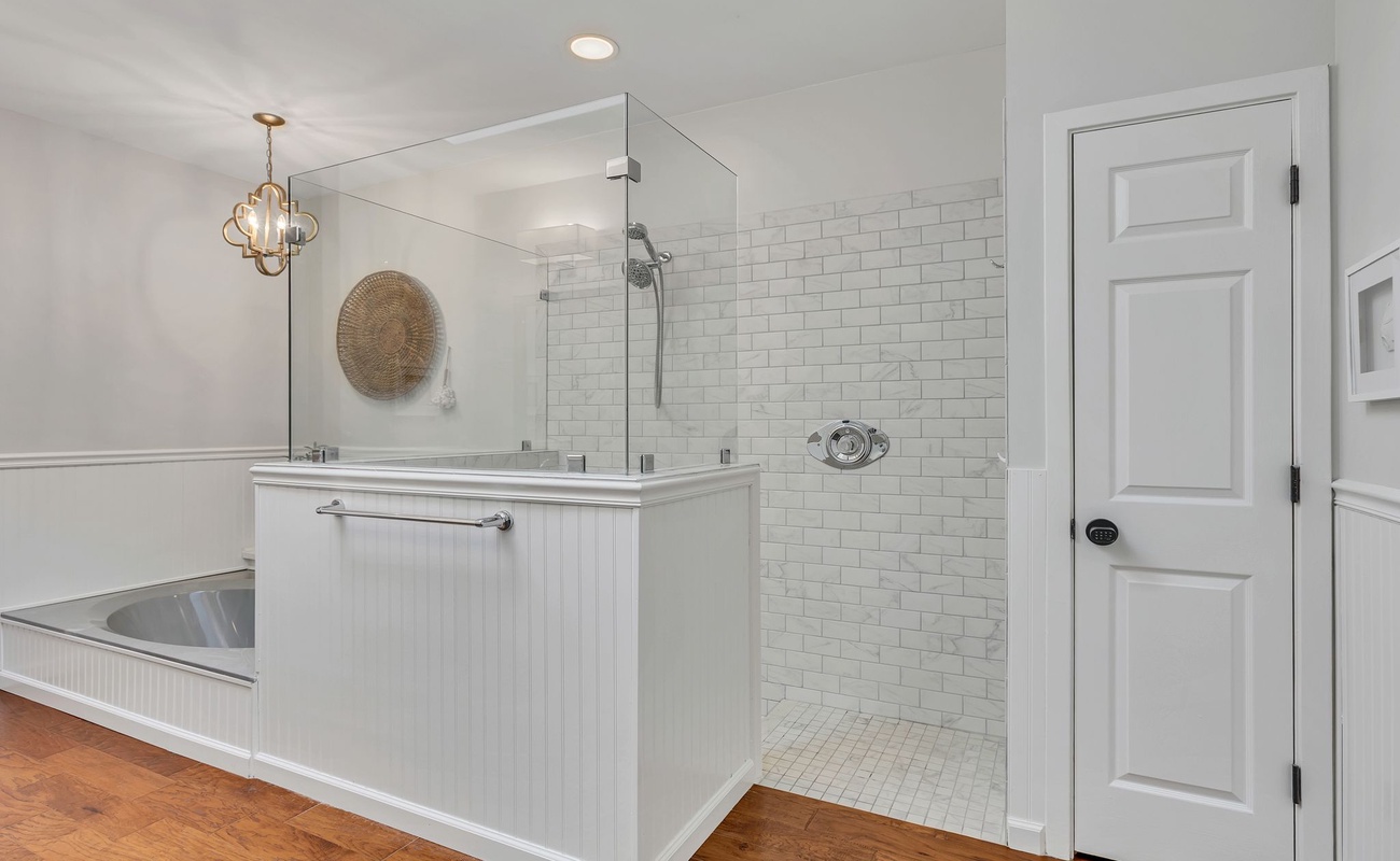 Unwind in your elegant bathroom featuring a luxurious soaking tub and spacious glass-enclosed shower with classic subway tile.