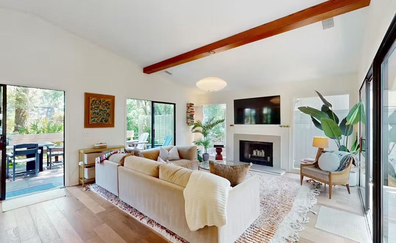 Unwind in your bright, airy living room where exposed beams and a cozy fireplace* create warmth while large windows flood the space with natural light.