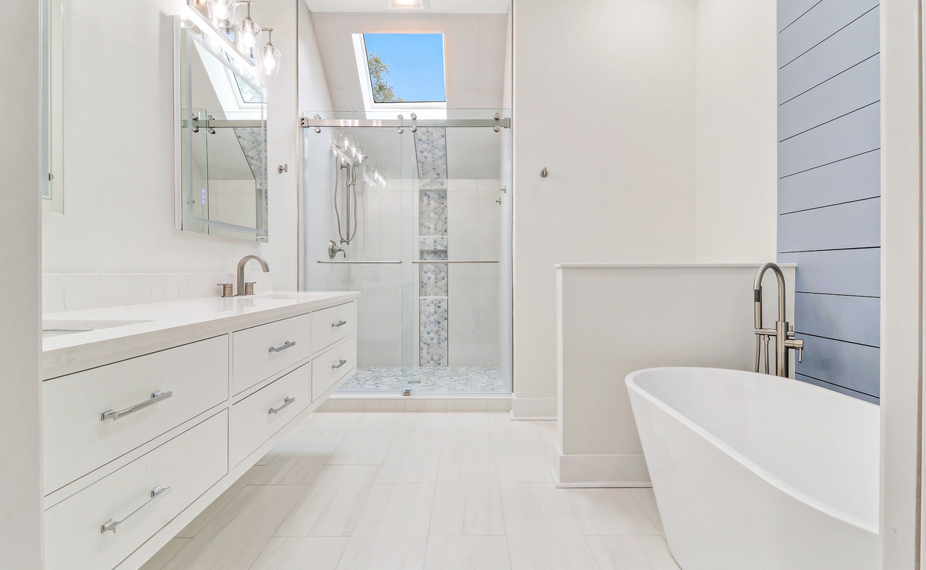 Indulge in luxury with your private spa-like bathroom featuring a soaking tub, glass shower, and abundant natural light streaming through the skylight.