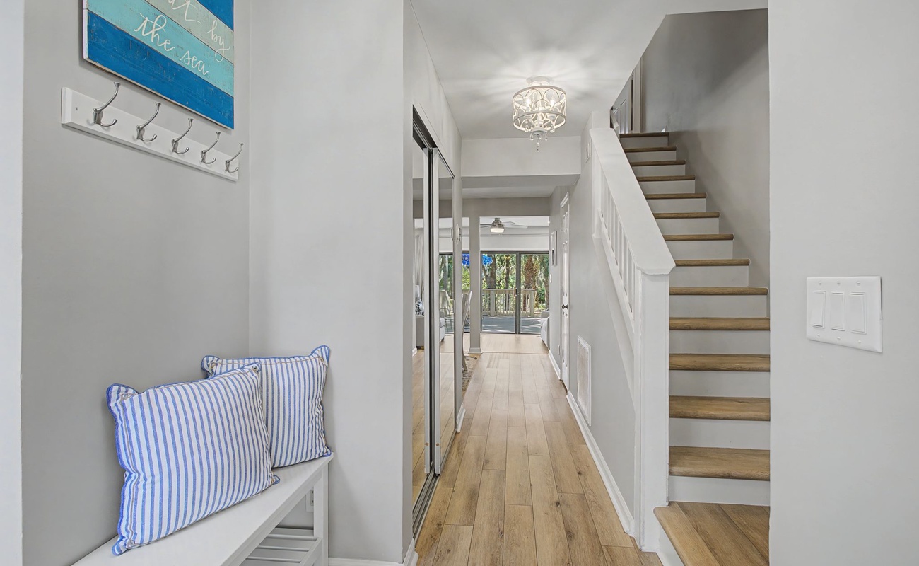 Step into your coastal-inspired entryway, where nautical charm meets modern elegance with coastal pillows and warm wood floors welcoming you home.