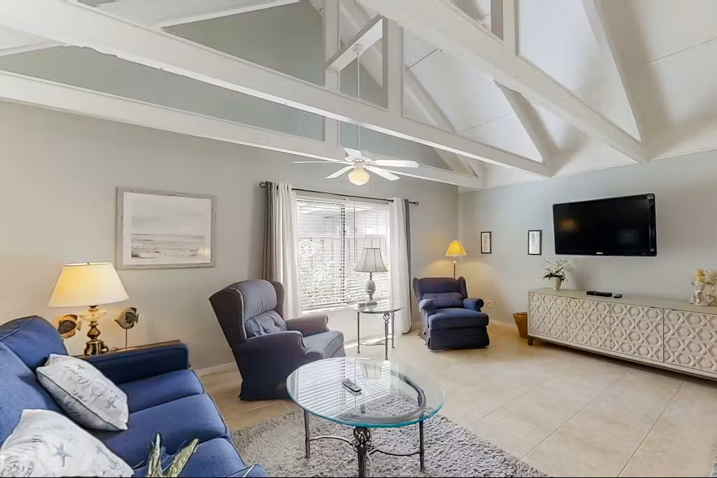 Relax in this bright living room with vaulted ceilings, cozy blue seating, and modern amenities for your perfect getaway.