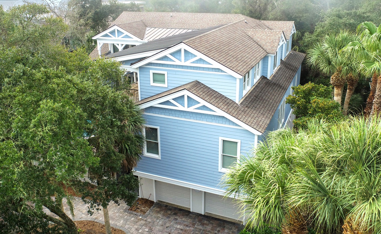 Charming coastal home nestled among lush tropical palms and mature landscaping in a peaceful residential setting.