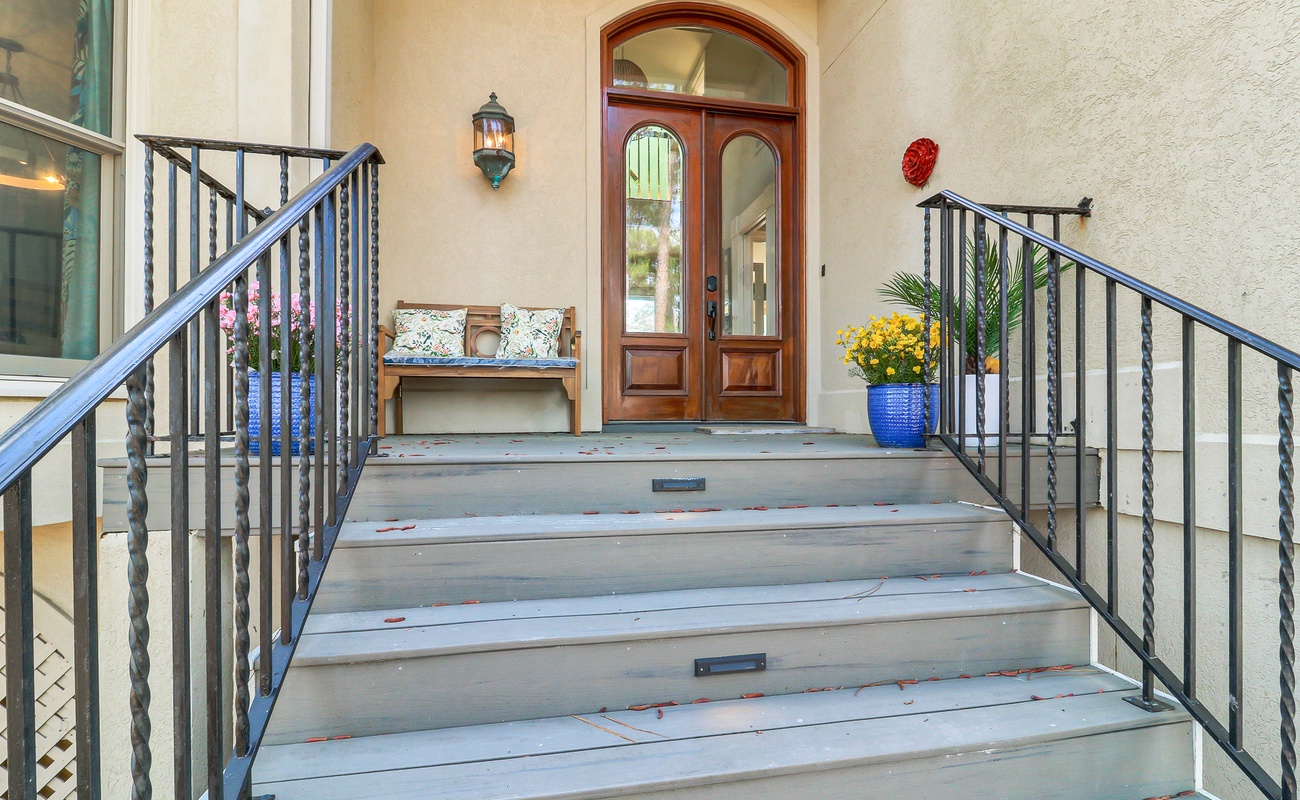 Elegant front entrance with wrought iron railings and charming bench welcomes you to your perfect getaway destination.