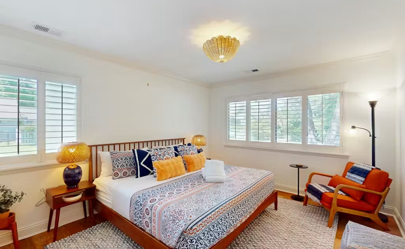 Drift off to sleep in this serene bedroom featuring a cozy mid-century bed, warm textures, and abundant natural light.