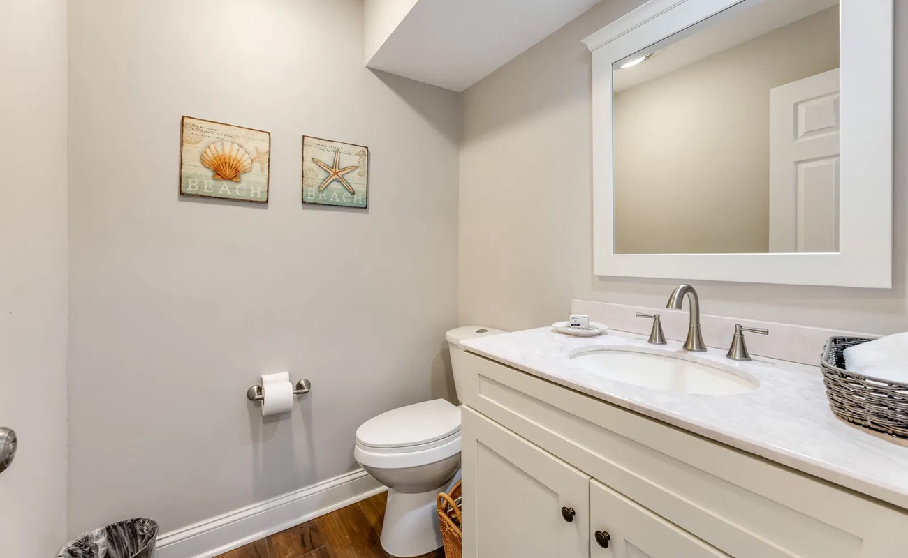 Step into your pristine bathroom featuring coastal charm with seashell artwork, marble countertops, and thoughtful touches that make freshening up a pleasure.