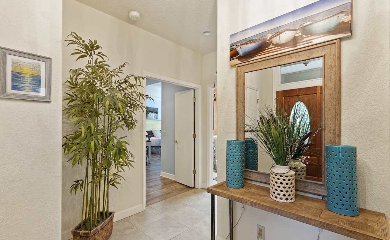 Step into your stylish coastal entryway where warm wood accents and tropical touches create an instant sense of relaxation and welcome.
