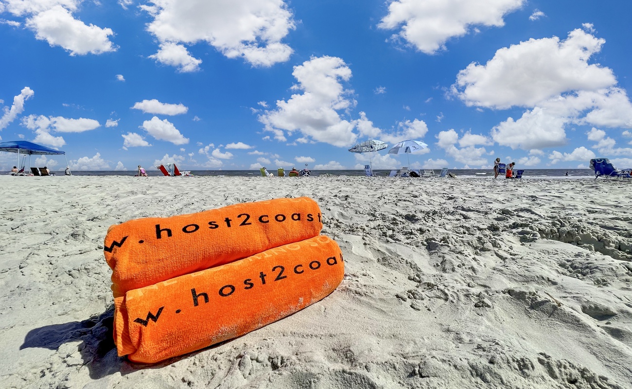 Beautiful sandy beach with bright blue skies and fluffy white clouds, perfect for relaxation and beach activities.