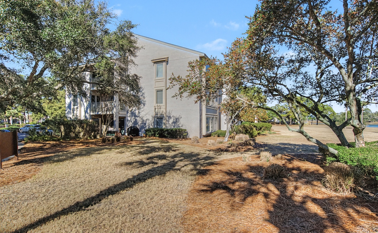 Modern coastal property nestled among mature trees with landscaped grounds and nearby waterfront access.