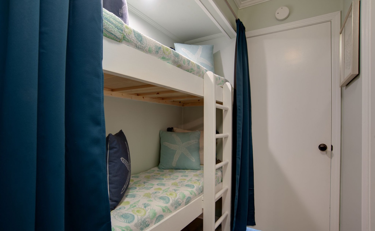 Your cozy bunk room features charming nautical bedding and privacy curtains, perfect for restful nights after beach adventures.