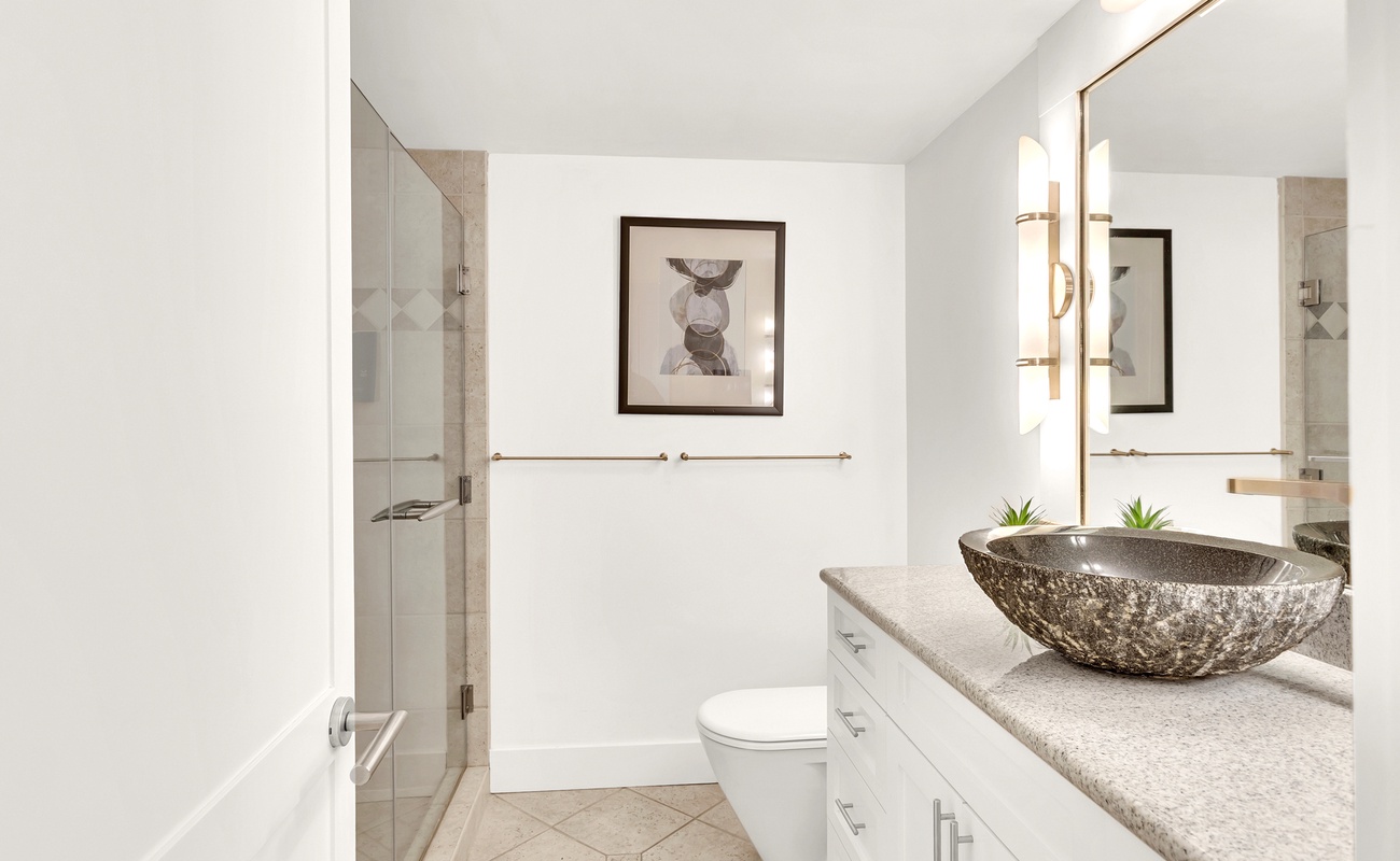 Unwind in your elegant bathroom featuring a stunning stone vessel sink and spacious walk-in shower with modern fixtures.
