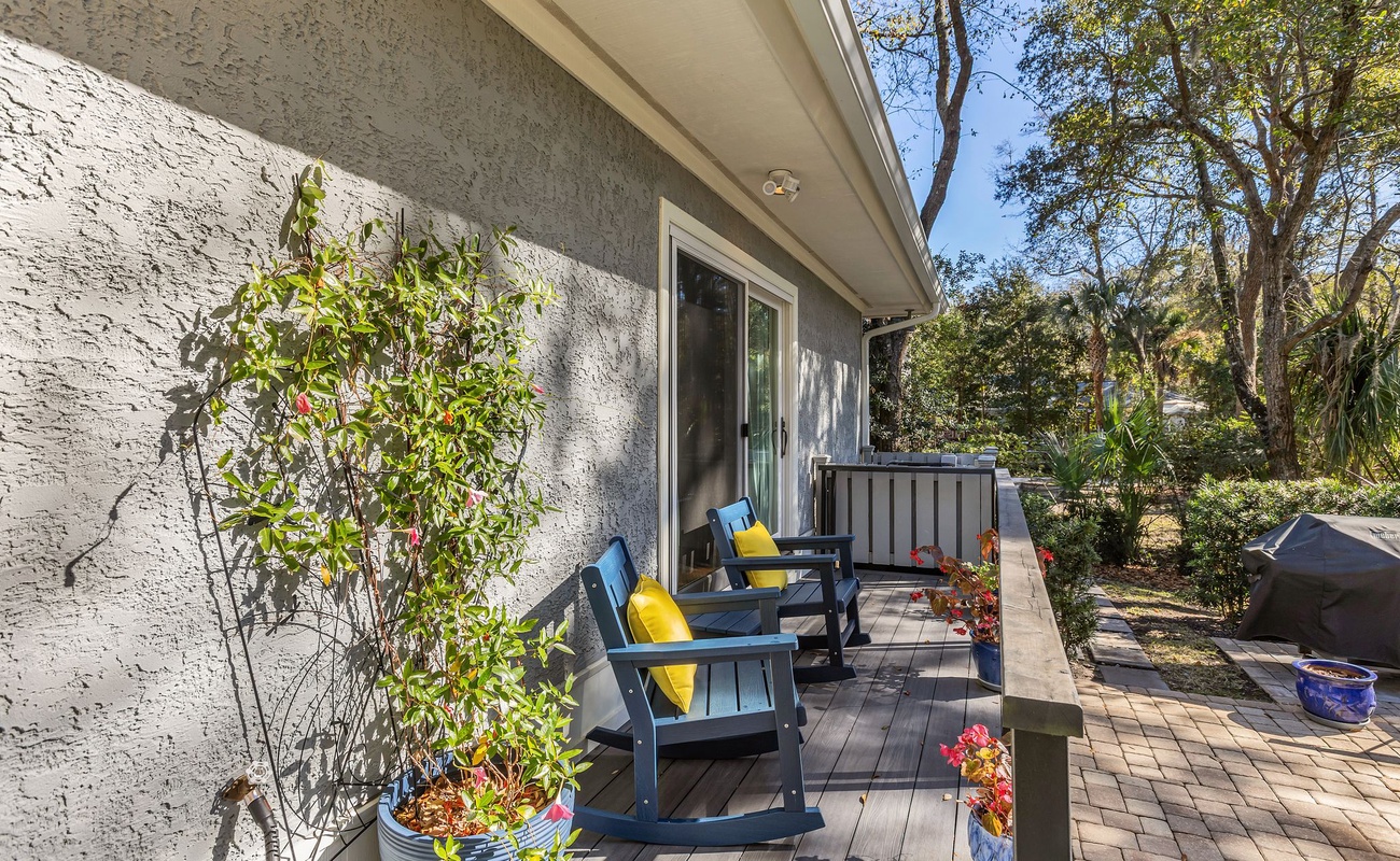 Your private deck awaits with colorful outdoor chairs and lush garden views, perfect for morning coffee or evening relaxation.