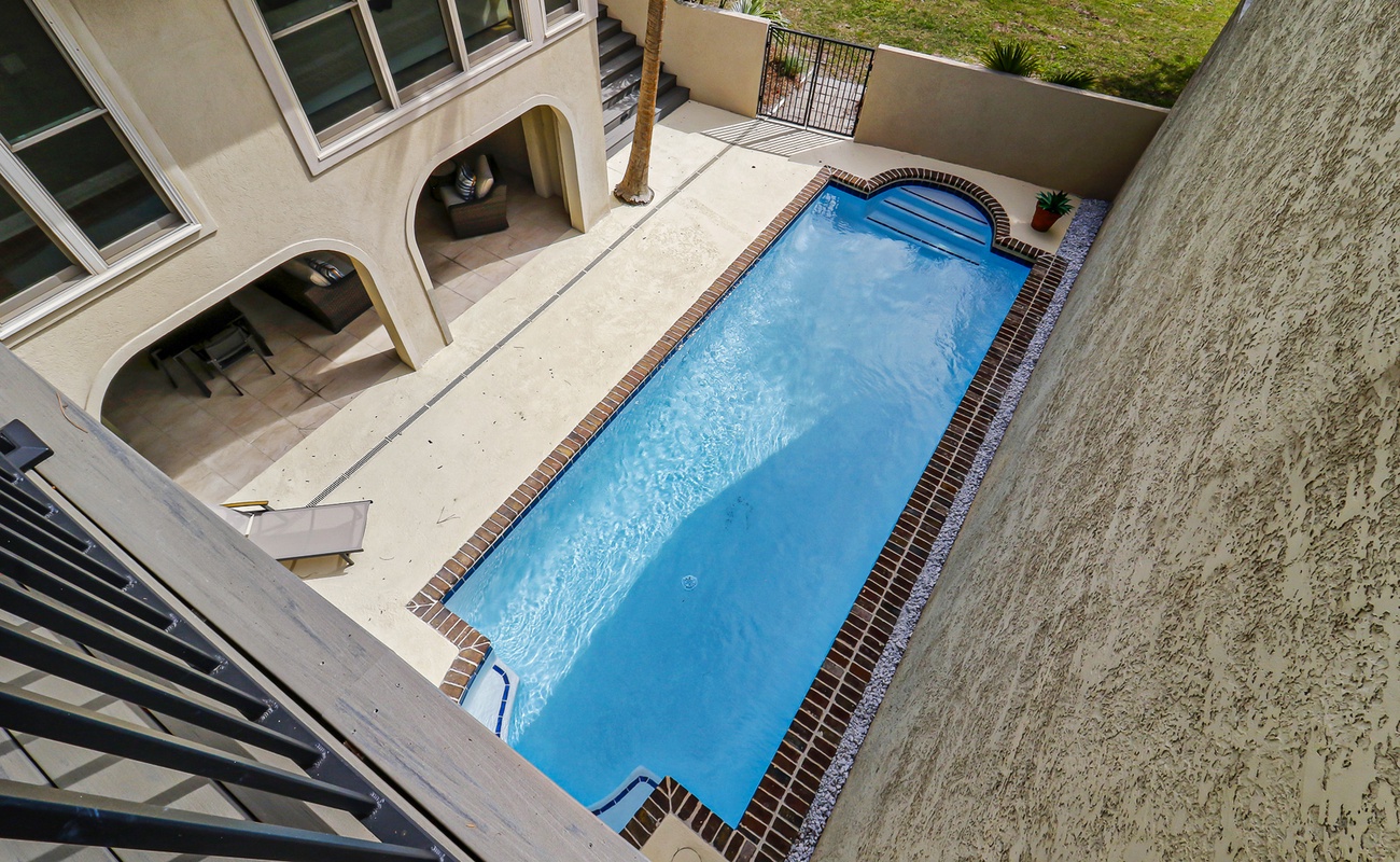 Aerial view of the property showing the private swimming pool and outdoor entertainment areas with covered seating spaces.
