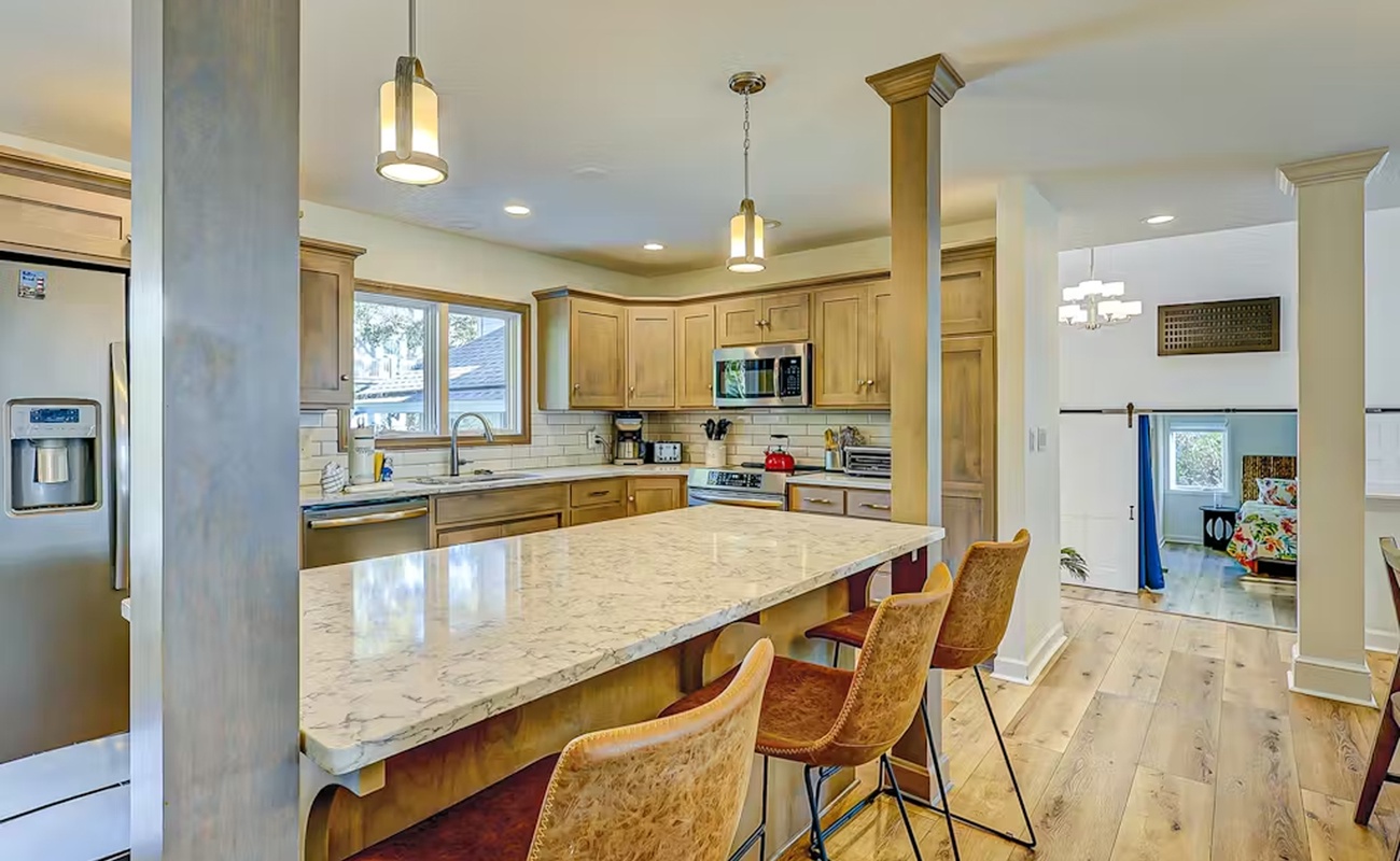 Gather around this stunning kitchen island where granite countertops and warm wood cabinetry create your perfect cooking and conversation space.