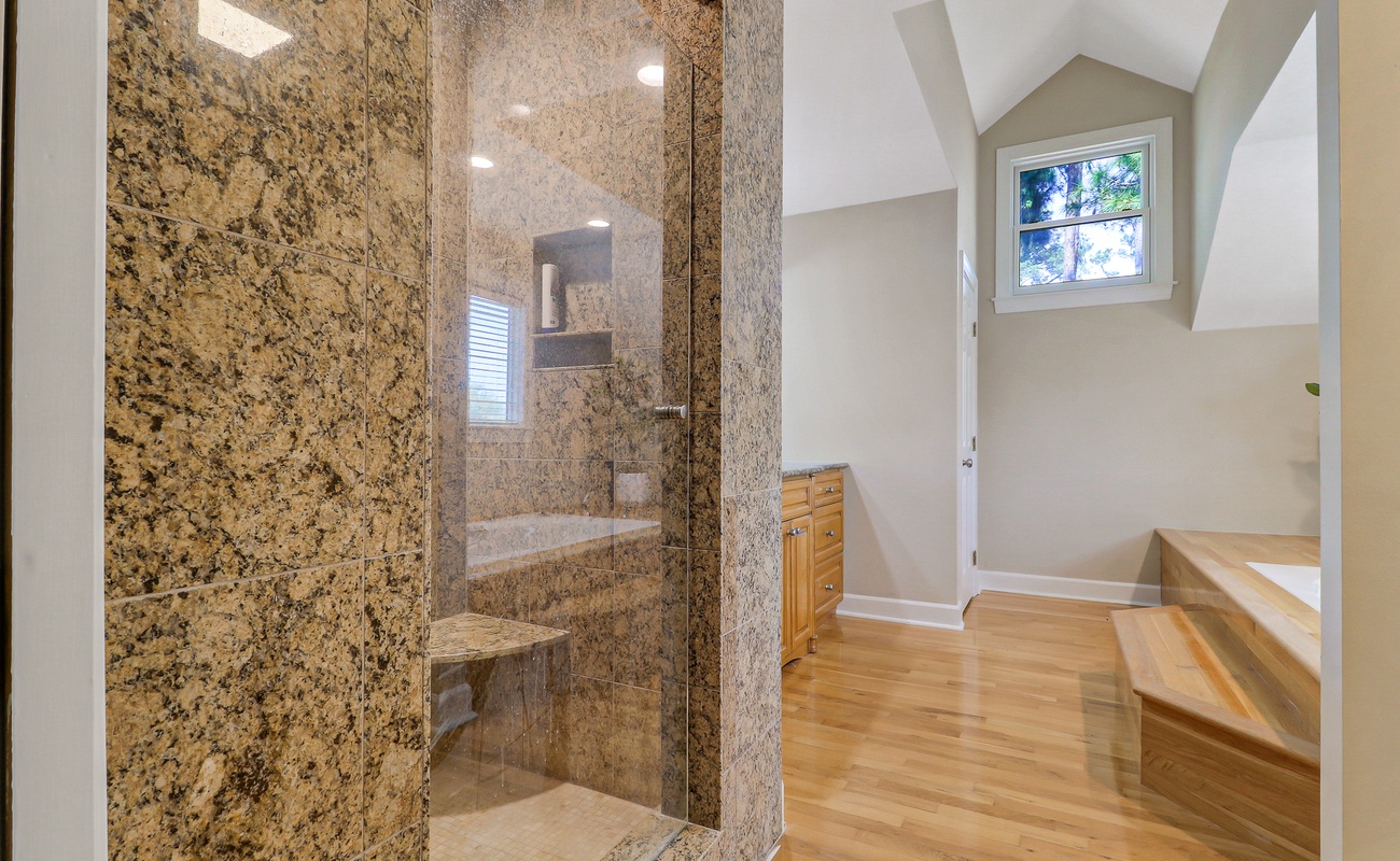 Luxurious granite shower with built-in seating offers your perfect morning retreat, while gleaming hardwood floors warm your feet throughout the bathroom.