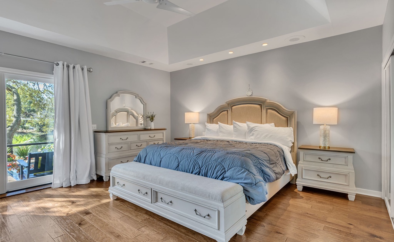 Relax in your peaceful bedroom sanctuary with elegant coastal furnishings, soft linens, and garden views from your private balcony.