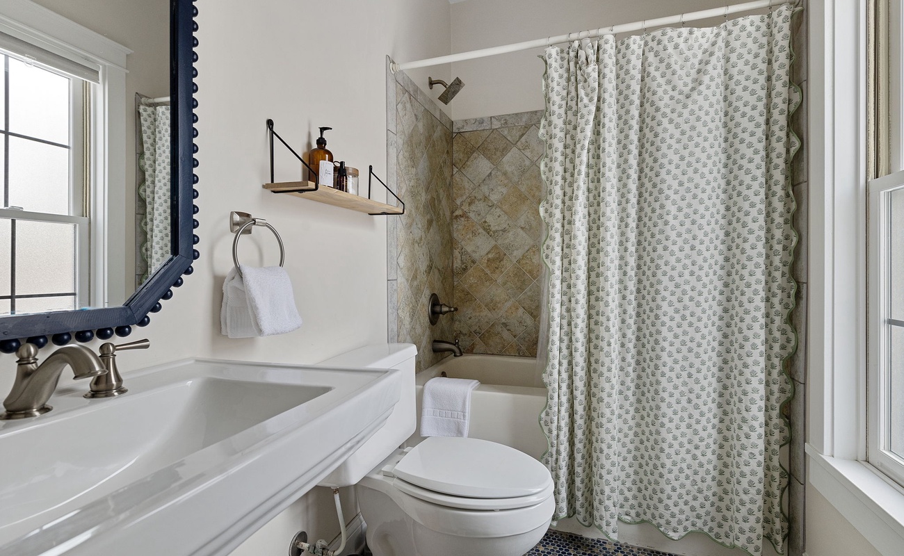 Well-lit bathroom with a gorgeous vanity + tiled tub-shower. What's not to like?