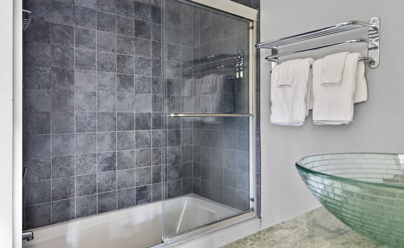 This sumptuous bathroom has a tiled shower-tub and glass-bowl vanity sink.