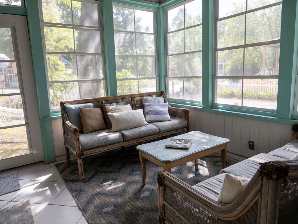 Sun-filled screened porch with wicker seating and garden views - always a favorite spot!